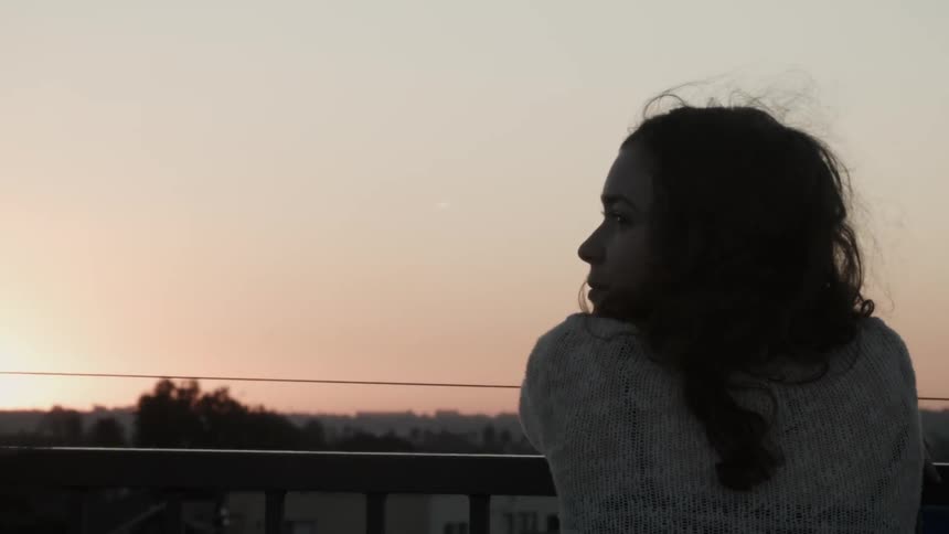 A woman is looking out over a view at sunset