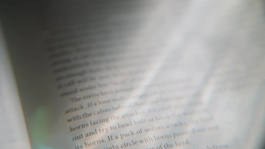 A close-up view of a magnifying glass moving down a page, revealing text about animal life