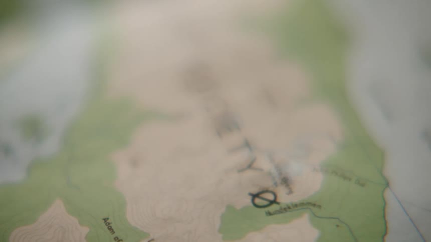 A close-up shot slowly pans across a topographical map, suggesting themes of travel, adventure, and exploration
