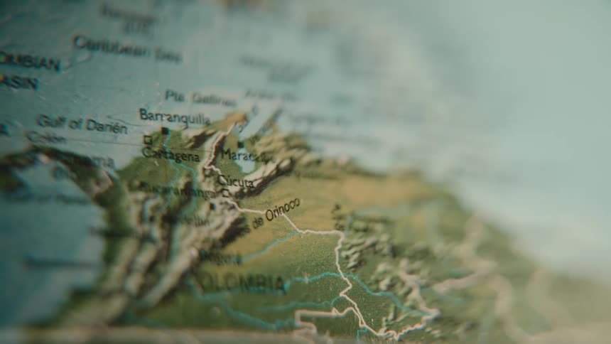A cinematic close-up of a world map revealing the countries of Colombia and Venezuela on the Caribbean Sea
