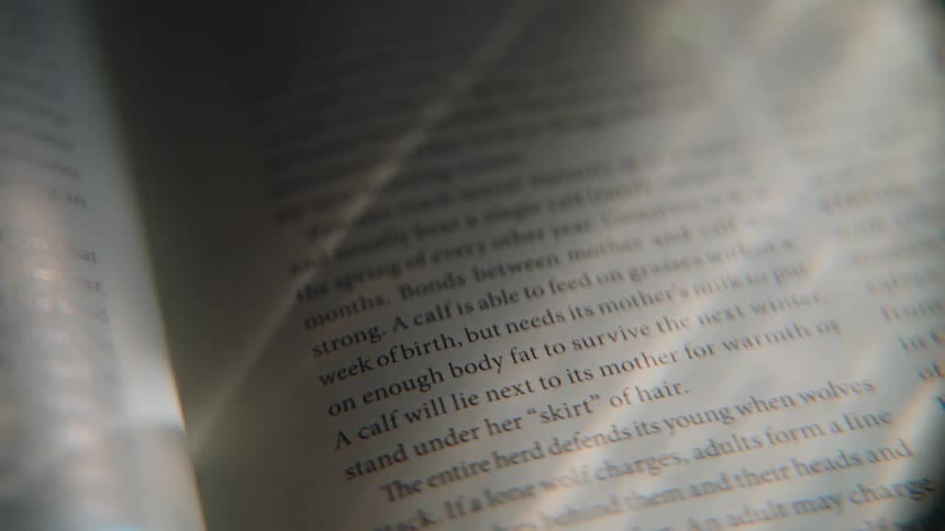 A close-up shot of text in a book about animal biology, viewed through a magnifying lens as light moves across the page