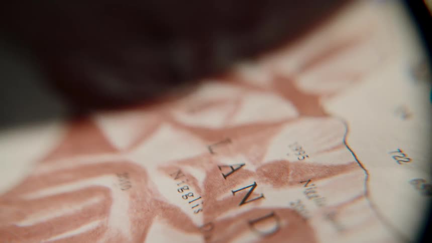 Extreme close-up shot panning across an old, topographical map of a fjord, creating a sense of adventure