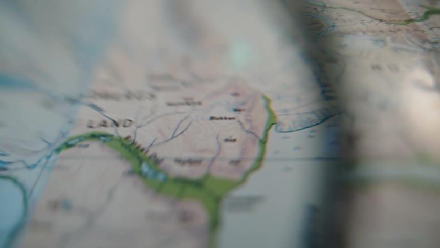 A slow, close-up pan across a detailed topographical map, suggesting travel planning or exploration
