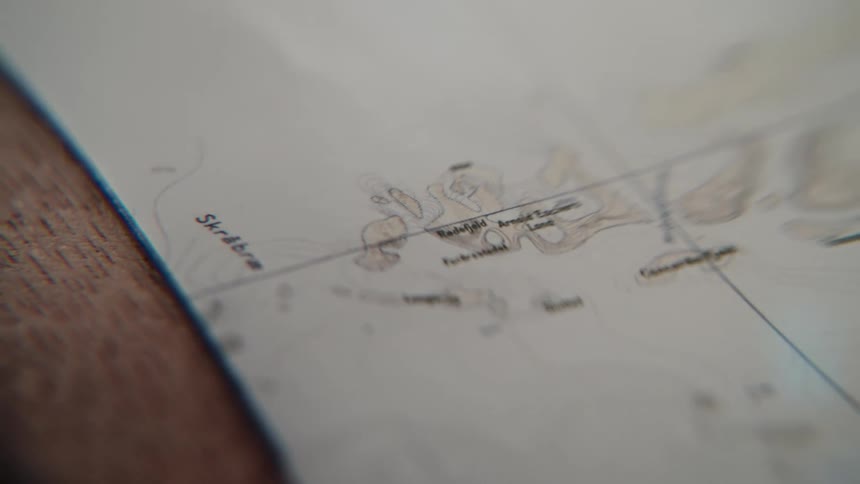 A magnifying glass slowly reveals the details on an old, vintage-style topographical map