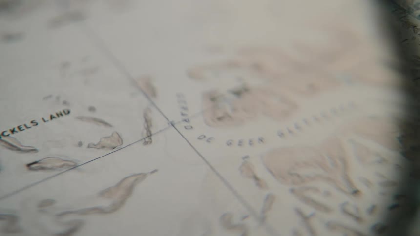 An extreme close-up shot slowly pans across an old, vintage map of arctic lands and glaciers