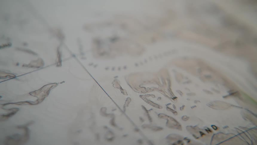 A slow pan reveals the intricate details of a vintage topographical map, suggesting adventure and exploration