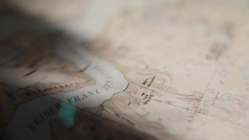 A dramatic close-up of a vintage-style map with shifting light and shadows, evoking a sense of adventure and planning