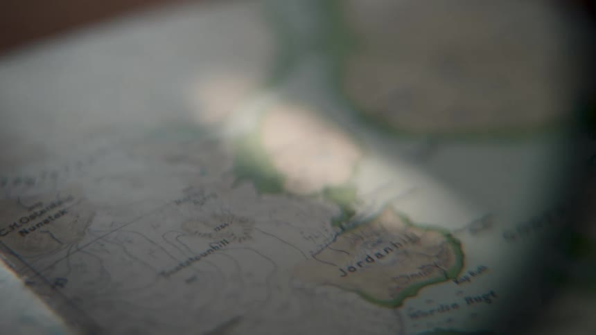 A beam of light slowly moves across a topographical map, illuminating a route for an expedition