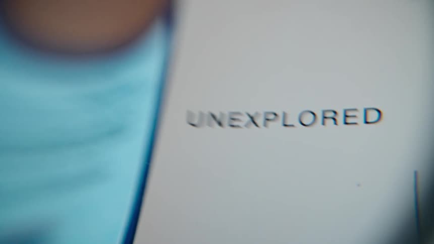 A macro shot focuses on the word 'unexplored' displayed on a digital screen, evoking a sense of adventure and discovery