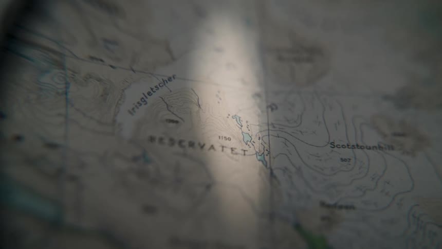 A beam of light slowly scans across a topographical map, highlighting the contours and details of the terrain