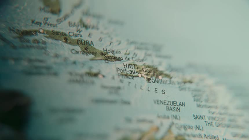 A macro close-up shot of a globe racks focus across the countries and islands of the Caribbean Sea, including Jamaica, Haiti, and Cuba