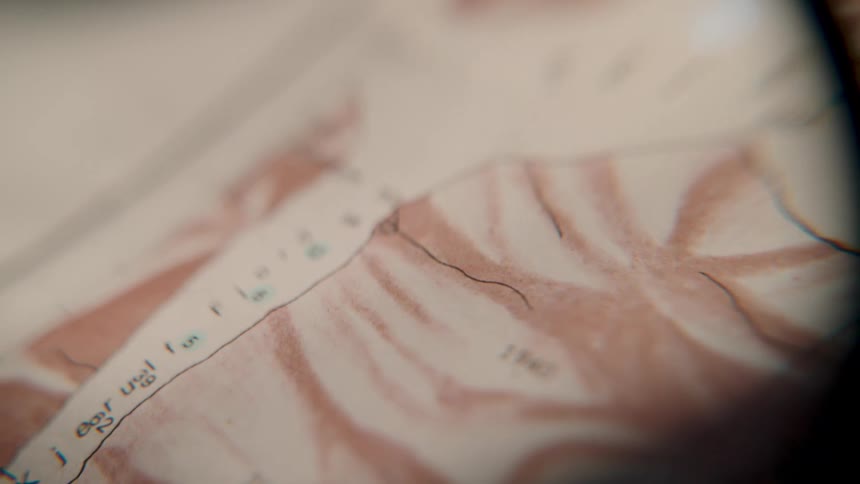 A very close-up, out-of-focus shot slowly reveals the details of an old, vintage map