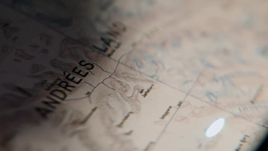 A mysterious close-up of a map of Andrées Land, a beam of light moving across the page