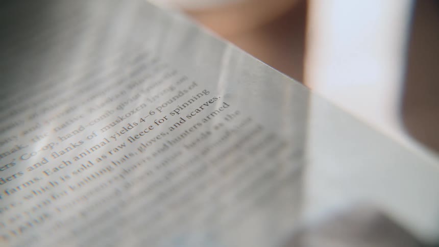 Sunlight slowly moves across the page of an open book, highlighting the text as it comes into focus