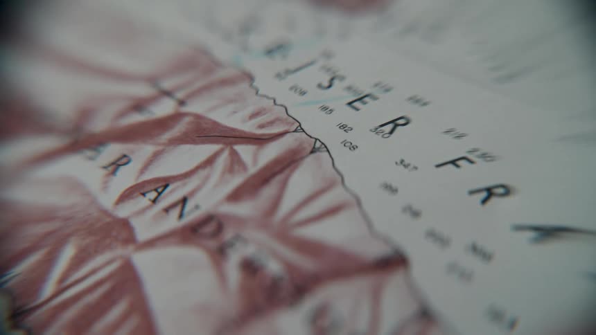 A cinematic close-up tracking shot reveals geographical locations and terrain on a vintage, atmospheric map