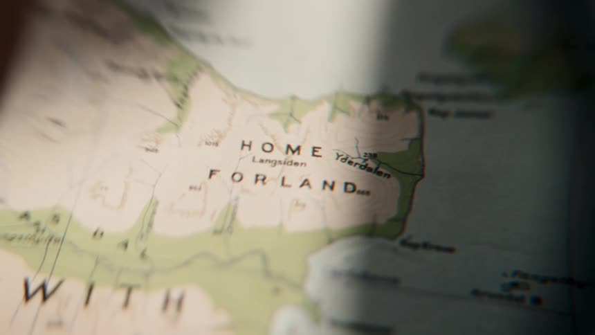 A person's point-of-view looking through a lens at a topographical map of a coastal region called Home Forland