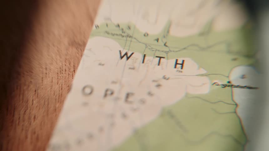 Slowly examining a vintage coastal map with a magnifying glass for an adventure