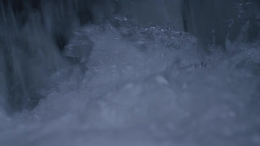An extreme close-up slow-motion shot captures the powerful and turbulent motion of cascading water