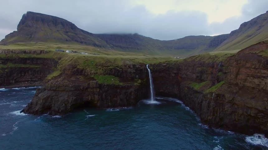 Small waterfall splashes off a cliff into the ocean