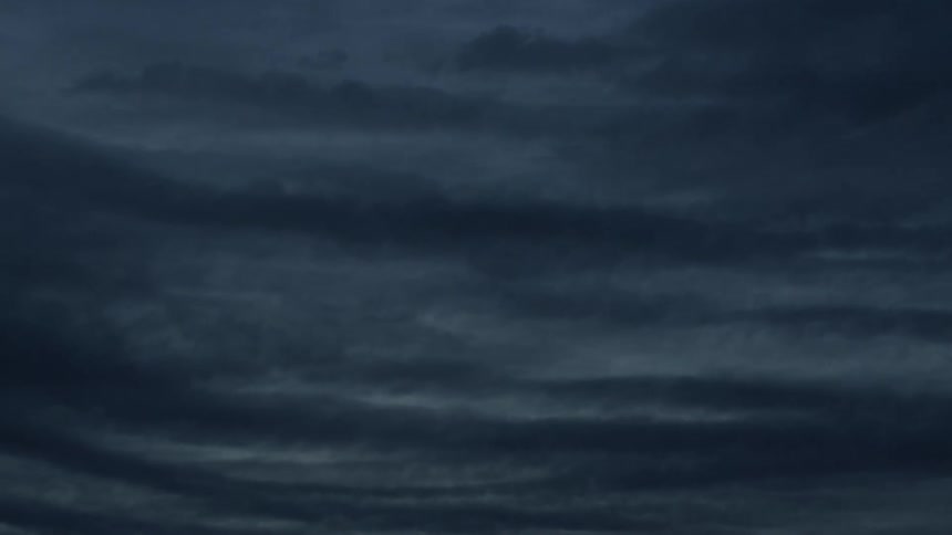 Dark, wavy storm clouds drift slowly across the ominous night sky in a time-lapse