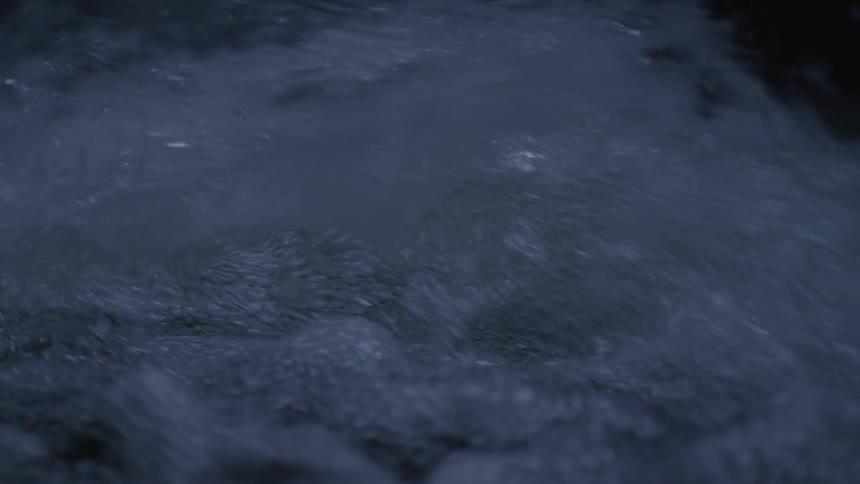A dramatic close-up slow-motion shot of dark, turbulent water churning powerfully