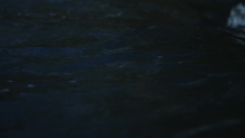 A mesmerizing slow-motion close-up of dark blue water flowing peacefully