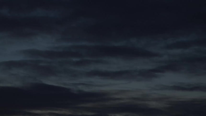 A somber evening sky is filled with dark, slow-moving clouds