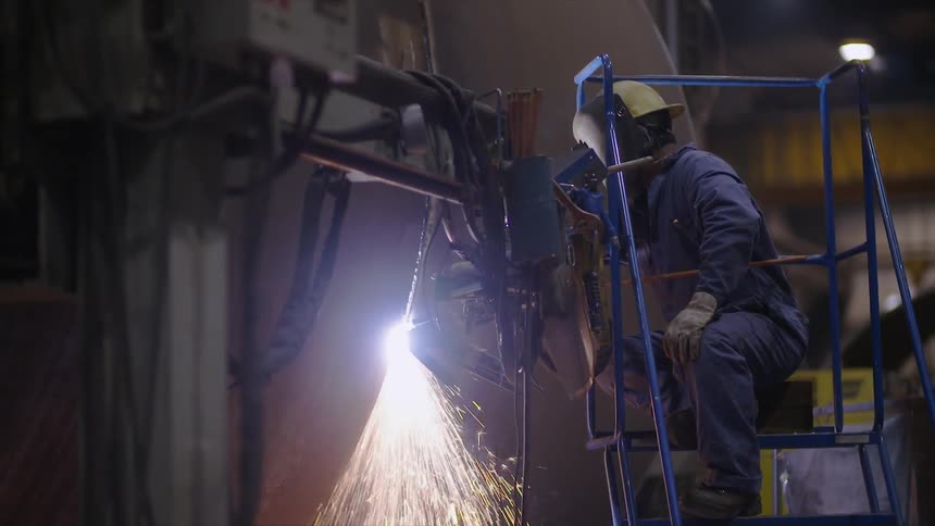 A man sits on a ladder welding