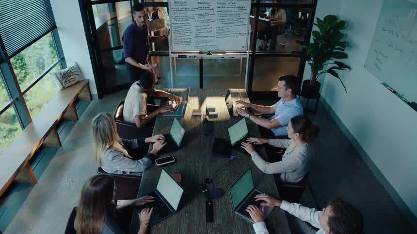 A diverse team of professionals collaborates during a presentation in a modern conference room with large windows
