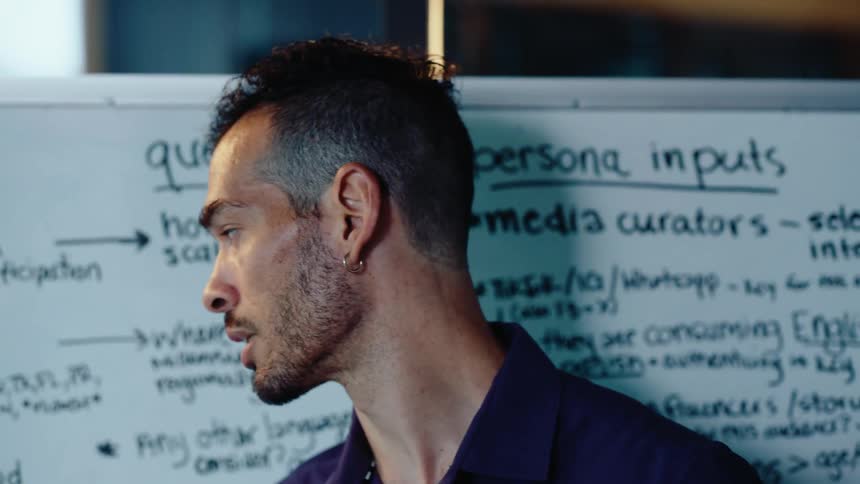 A focused young professional presents business ideas and strategies in front of a whiteboard during a meeting