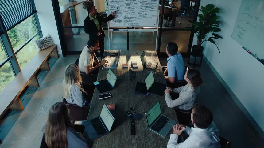 A high-angle view of a diverse business team collaborating during a presentation in a modern office conference room