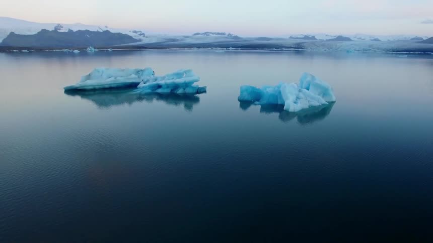 Icebergs float in the ocean off a shoreline