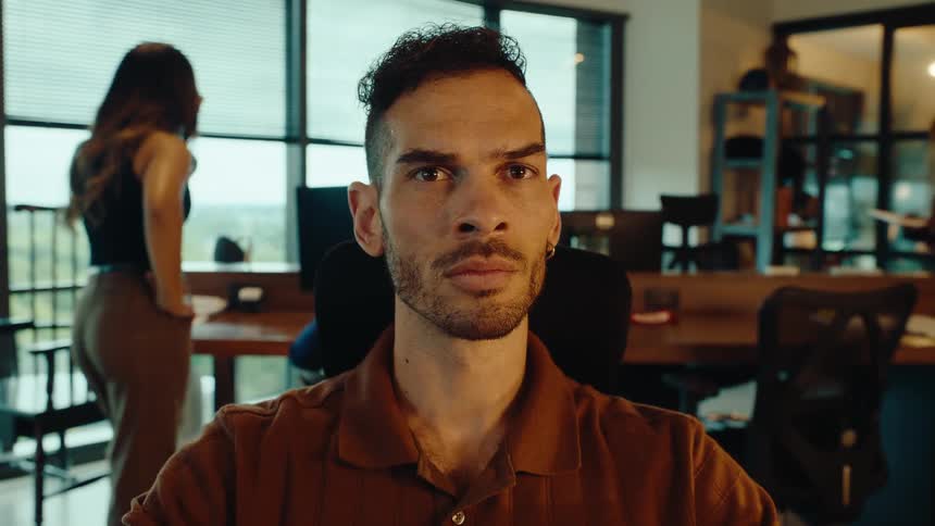 From a close-up of hands typing, the camera tilts up to reveal a young man's focused face working in a modern office