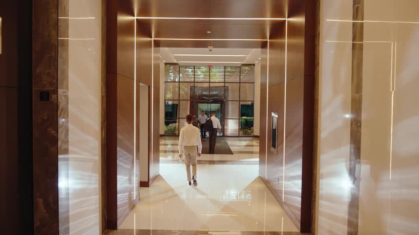 Professionals walk through a modern and brightly lit corridor of a corporate office building