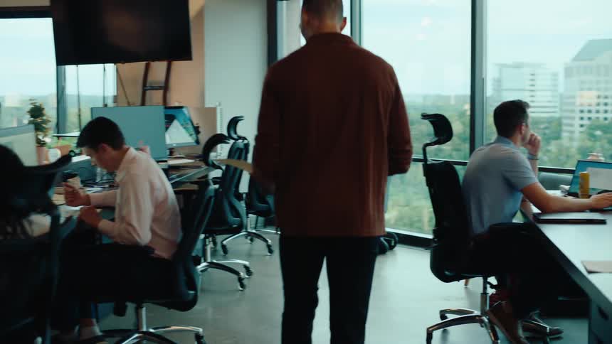Slow motion tracking shot of a woman handing a folder to a man in a modern open-concept office