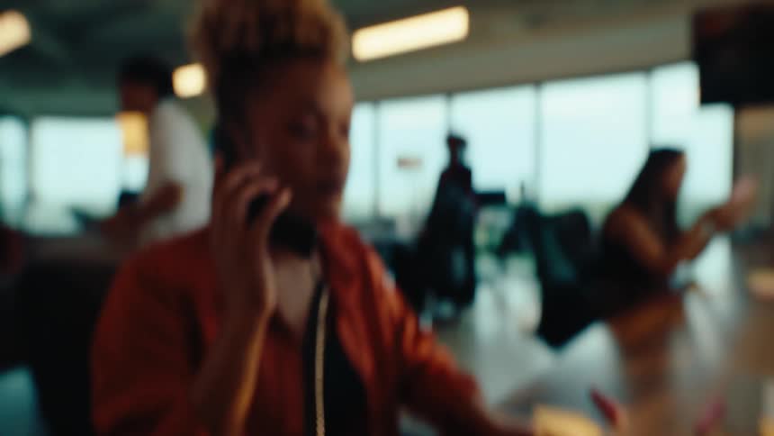 A woman answers a landline phone at her desk in a modern, bustling office