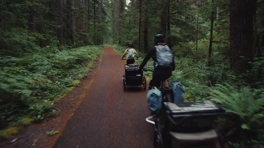 Following two adventurous cyclists on a bikepacking journey down a remote, paved trail through a lush green forest