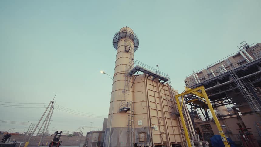 Slow push-in shot of a tall smokestack at a large industrial power plant facility at dawn