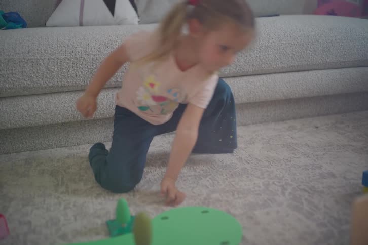 A young girl with pigtails finishes playing with her toys and gets up to dance in her sun-drenched living room