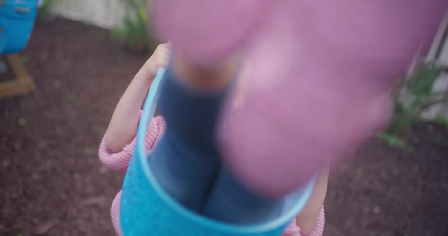 A cute little girl with a purple bow in her hair smiles as she swings back and forth in her backyard in slow motion