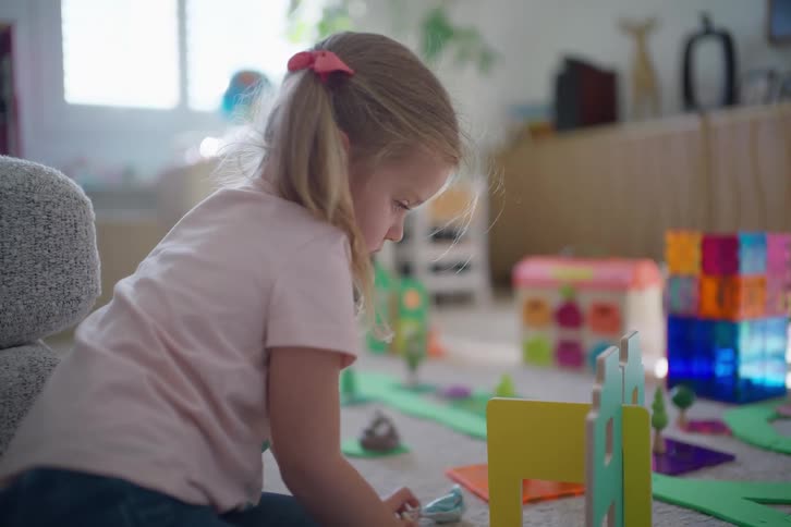 A cute little girl is absorbed in imaginative play with her colorful toys in a bright living room