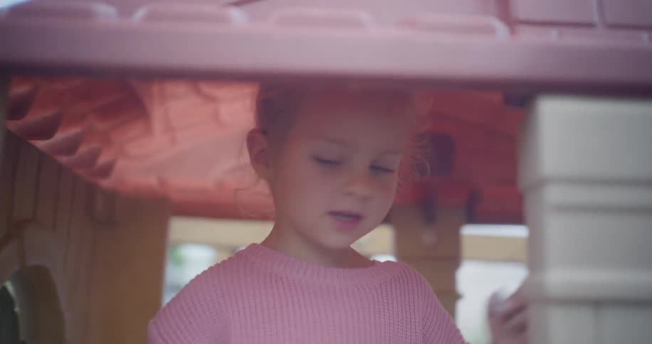 Slow motion shot of an inquisitive young girl pointing and exploring inside a playhouse