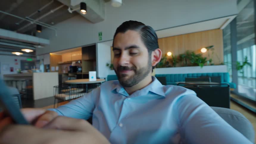 A disorienting spinning effect reveals a businessman smiling at his smartphone in a modern co-working space