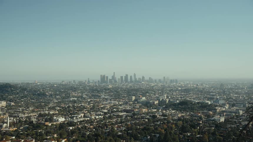 A wide, static shot of the sprawling Los Angeles cityscape with the downtown skyline visible on a clear, sunny day
