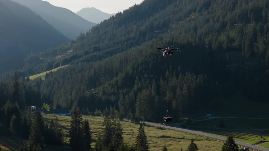 An industrial heavy-lift drone transports a cargo container through a beautiful, remote mountain valley