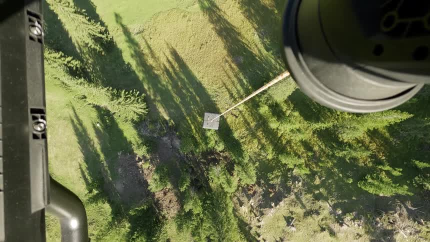 A vertical, top-down point of view from a chairlift moving over a lush green pine tree forest on a sunny day