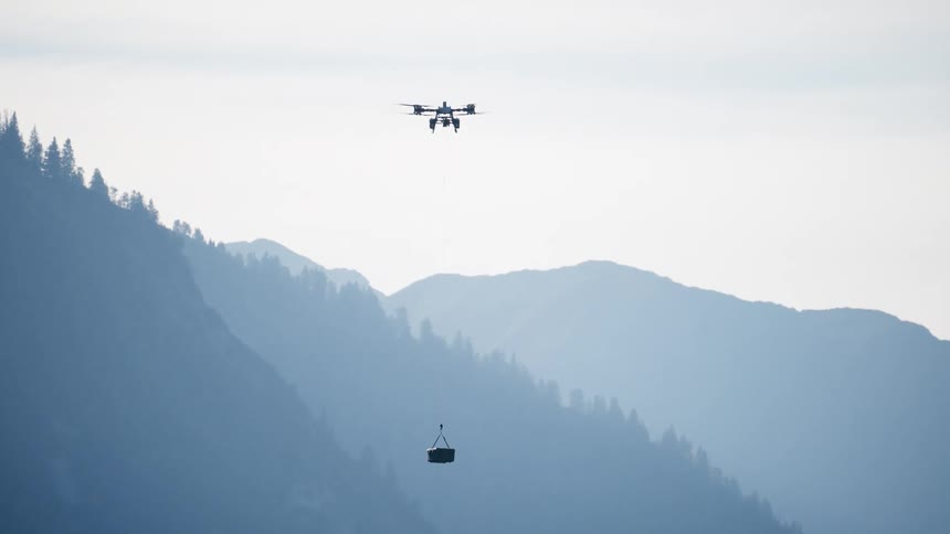 A delivery drone carries a package while hovering in front of a majestic, hazy mountain range