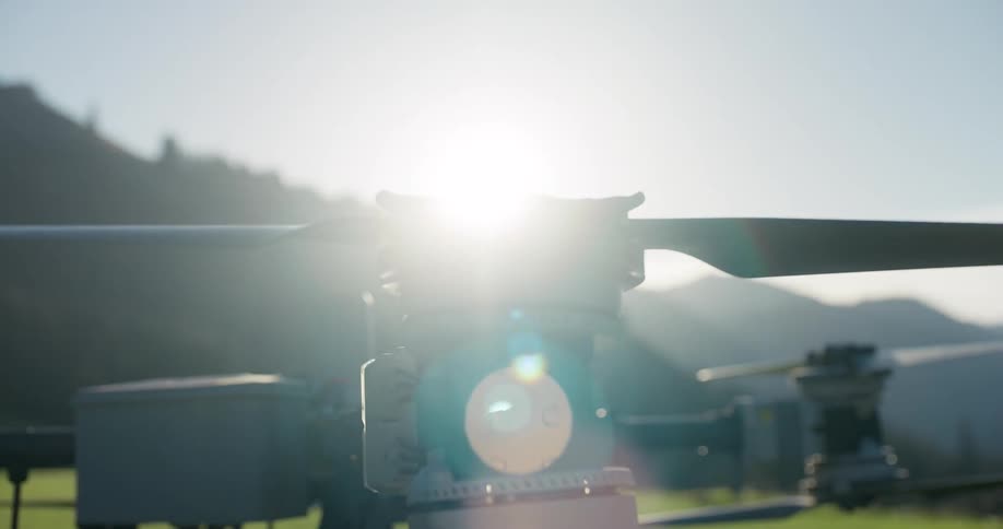 Dramatic close-up of a high-tech drone's propeller spinning in slow motion with the sun flaring brightly behind it