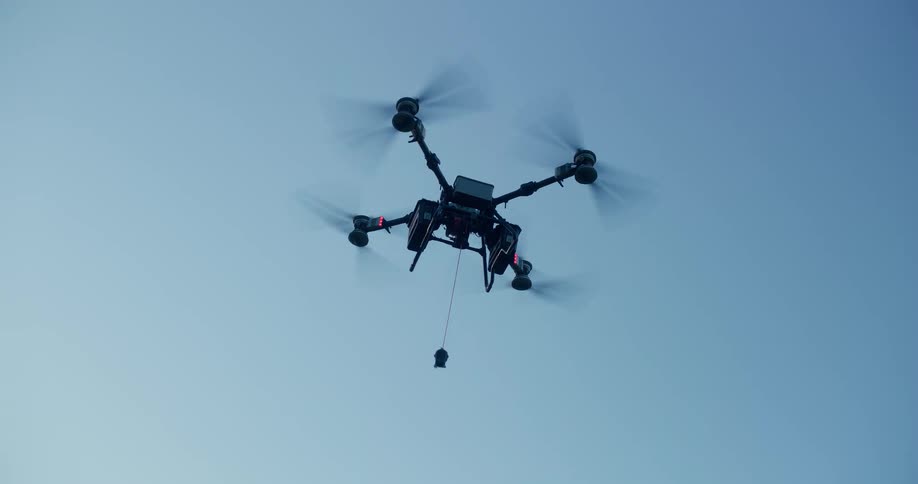 A low-angle shot of a professional hexacopter drone hovering in place against a clear blue sky