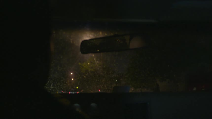 A car is driving in the rain at night